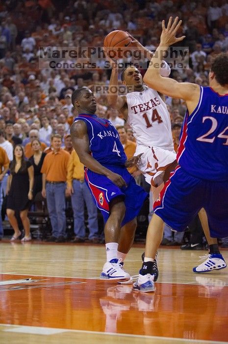 UT sophomore D.J. Augustin (#14, G) takes a shot with KU senior Sasha Kaun (#24, Center) and KU sophomore Sherron Collins (#4, Guard) guarding him.  The University of Texas (UT) Longhorns defeated the University of Kansas Jayhawks 72-69 in Austin, Texas on Monday, February 11, 2008.

Filename: SRM_20080211_2155368.jpg
Aperture: f/2.8
Shutter Speed: 1/640
Body: Canon EOS-1D Mark II
Lens: Canon EF 80-200mm f/2.8 L