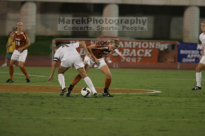 UT freshman Kylie Doniak (#15, Midfielder) tackles the ball as UT sophomore Erica Campanelli (#19, Defender) watches.  The University of Texas women's soccer team tied 0-0 against the Texas A&M Aggies Friday night, September 27, 2008.

Filename: SRM_20080926_1942041.jpg
Aperture: f/4.0
Shutter Speed: 1/500
Body: Canon EOS-1D Mark II
Lens: Canon EF 300mm f/2.8 L IS