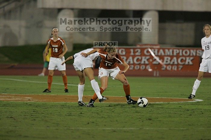 UT freshman Kylie Doniak (#15, Midfielder) tackles the ball as UT sophomore Erica Campanelli (#19, Defender) watches.  The University of Texas women's soccer team tied 0-0 against the Texas A&M Aggies Friday night, September 27, 2008.

Filename: SRM_20080926_1942088.jpg
Aperture: f/4.0
Shutter Speed: 1/500
Body: Canon EOS-1D Mark II
Lens: Canon EF 300mm f/2.8 L IS